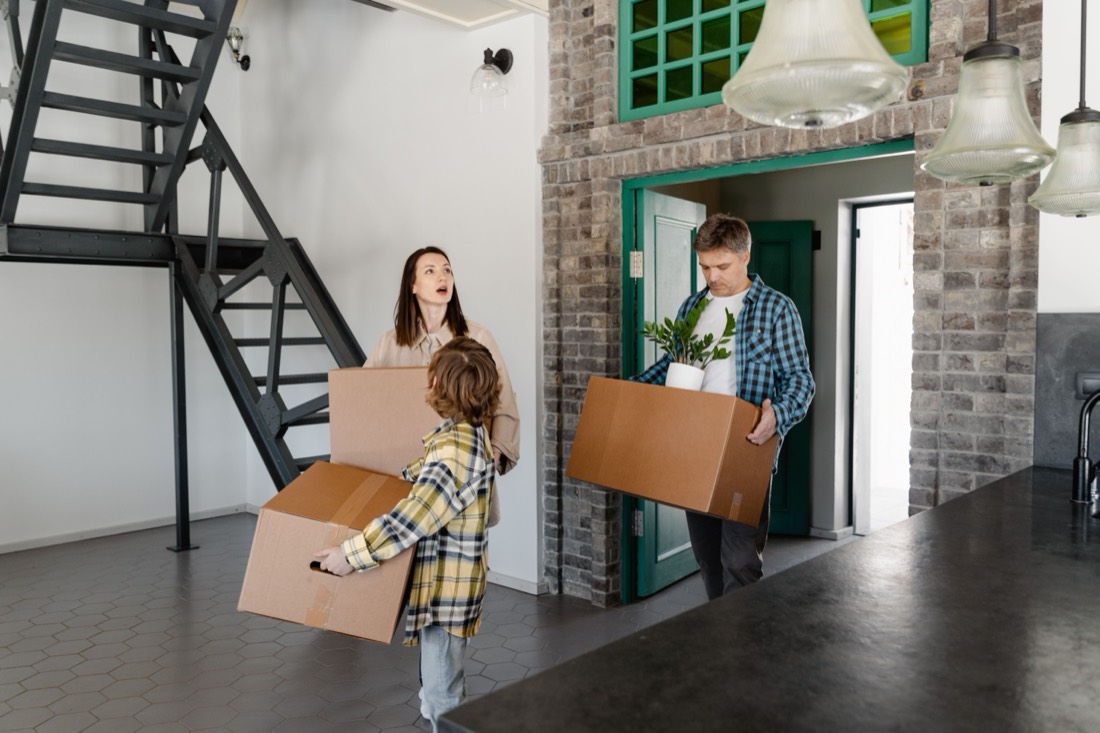 Familie trägt Kartons in die neue Wohnung