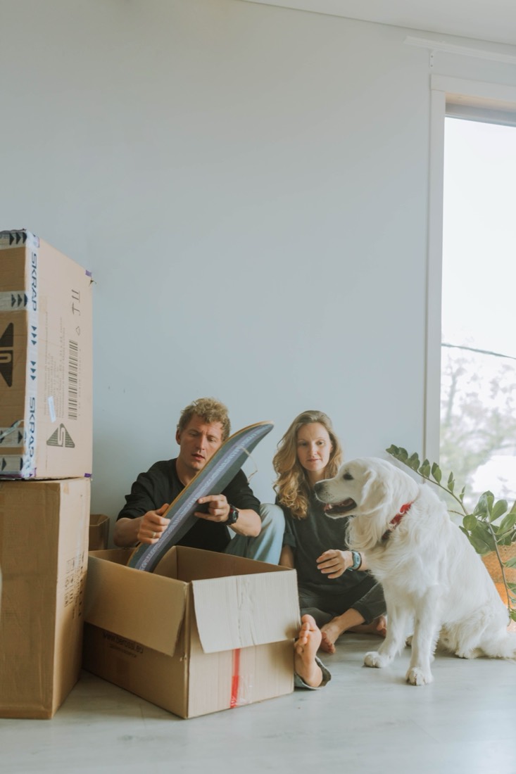 Paar mit Hund und Umzugskartons in der neuen Wohnung